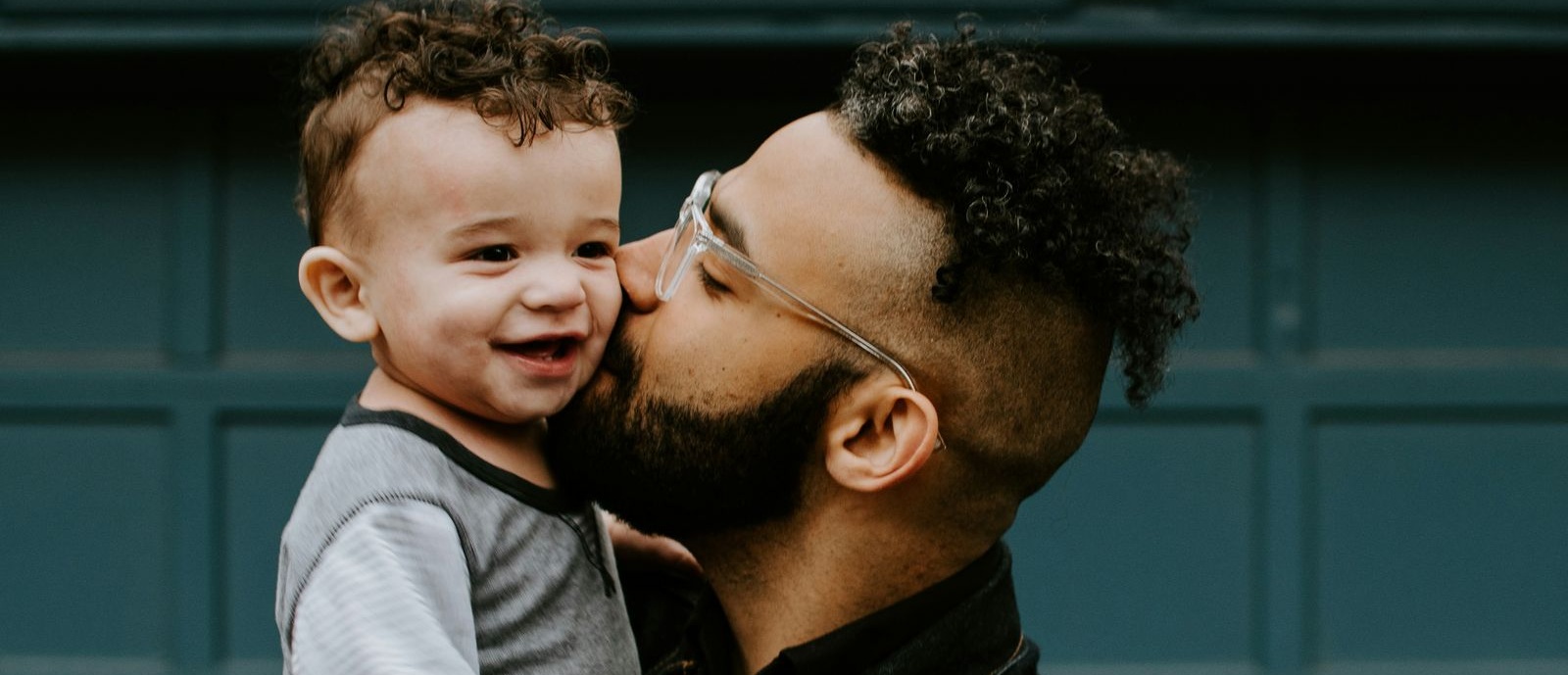 Man wearing glasses with a smiling toddler.